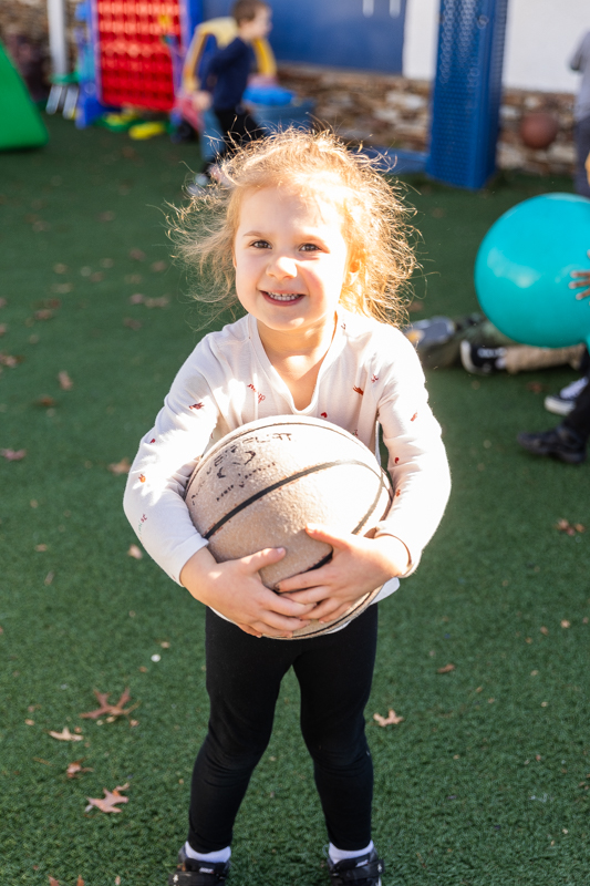 girl holding a basketball and smiling